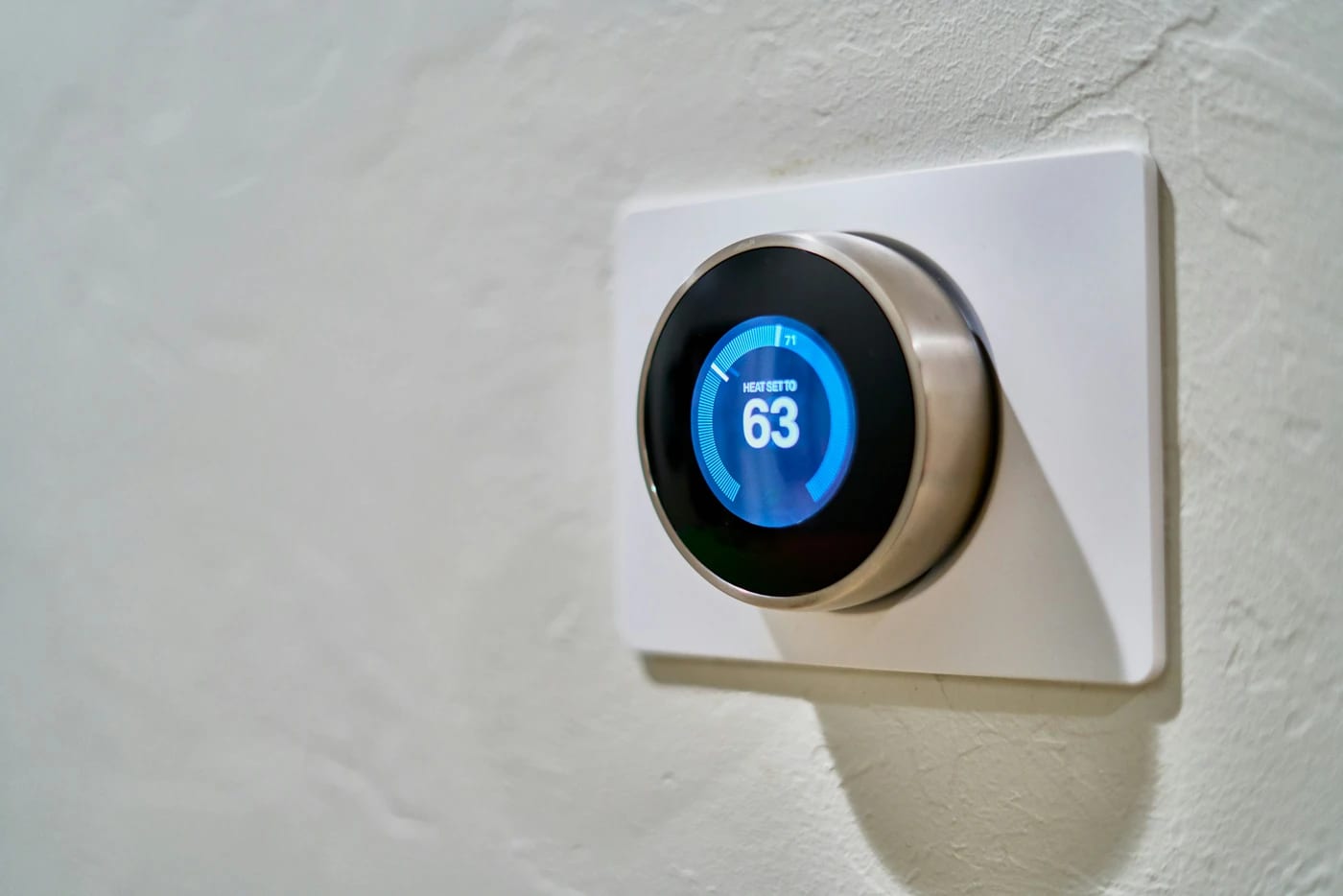 Thermostat connecté fixé au mur, affichant la température de consigne