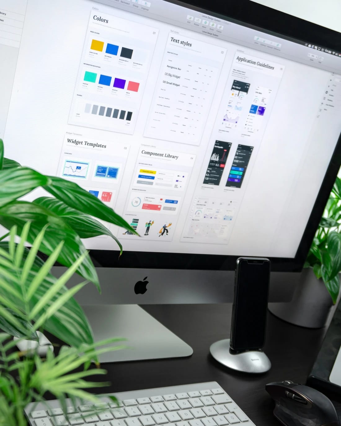 Écran affichant une charte graphique et des maquettes d’interface, entouré de plantes