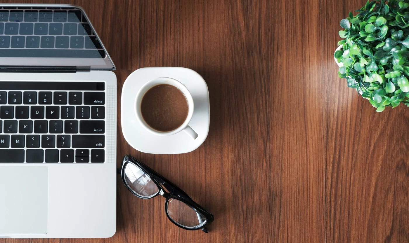 Ordinateur portable, tasse de café et plante sur un bureau en bois
