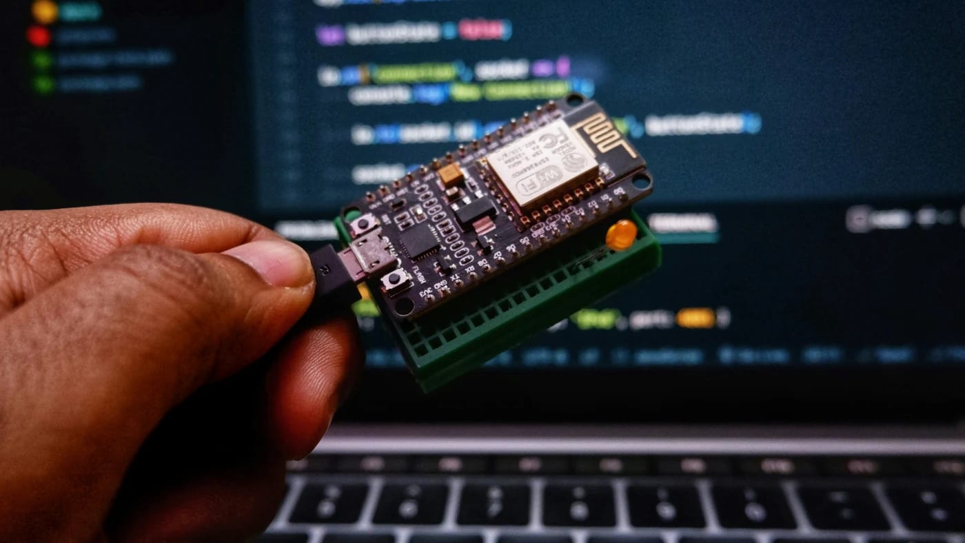 Module Wi-Fi à microcontrôleur tenu devant un écran de code