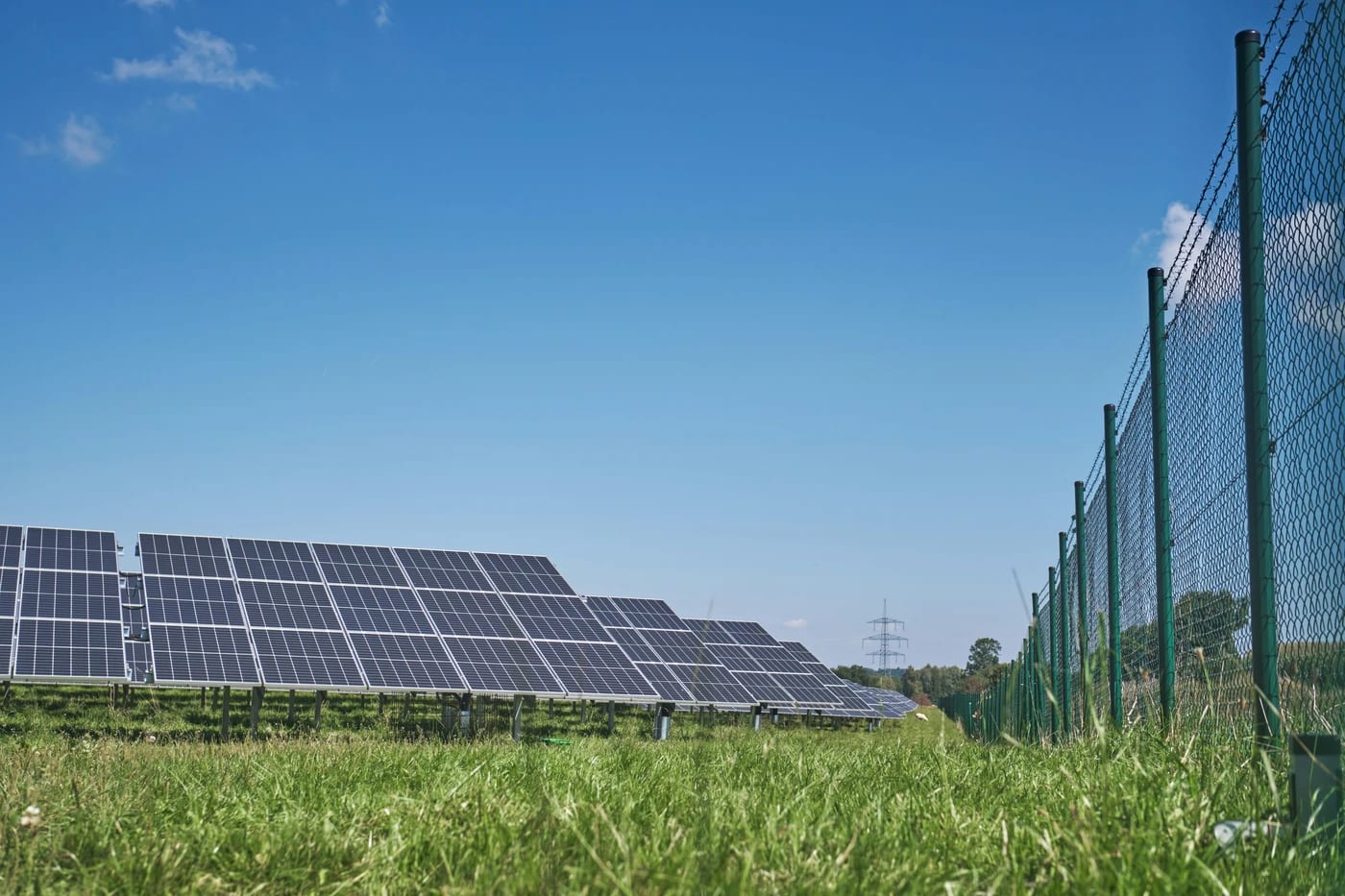 Rangée de panneaux solaires dans un pré, sous un ciel bleu